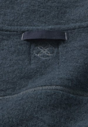 Fleece-Bekleidung in Dunkelblau mit glatter Textur. Mit einer genähten Naht und einem dezenten Logopatch in der oberen Mitte.