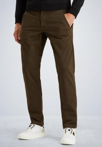 Brune bomulds chinos med slim fit, der har forlommer, en glat tekstur, og som er parret med hvide og beige sneakers.