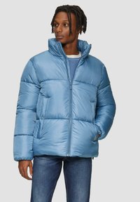 Lichtblauwe pufferjack met een hoge kraag, een rits aan de voorkant en twee zijzakken. Glad, glanzend materiaal met doorgestikte secties en elastische manchetten.