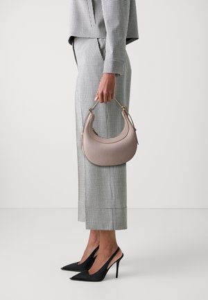 Hobo-veske i lys beige skinn med en strukturert form, gullfargede detaljer og ett håndtak, kombinert med et svart og hvitt rutete antrekk.