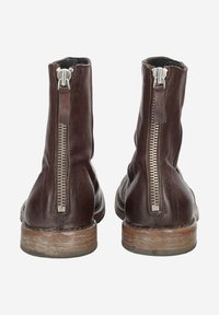 Bottines en cuir marron avec une finition lisse, dotées d'une fermeture éclair en métal argenté à l'arrière et d'une semelle texturée marron.