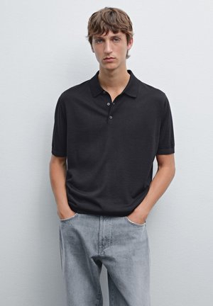 Sort kortærmet polo-Shirt med klassisk krave, der har en glat overflade og en tre-knaps knapliste, parret med lyse grå jeans.