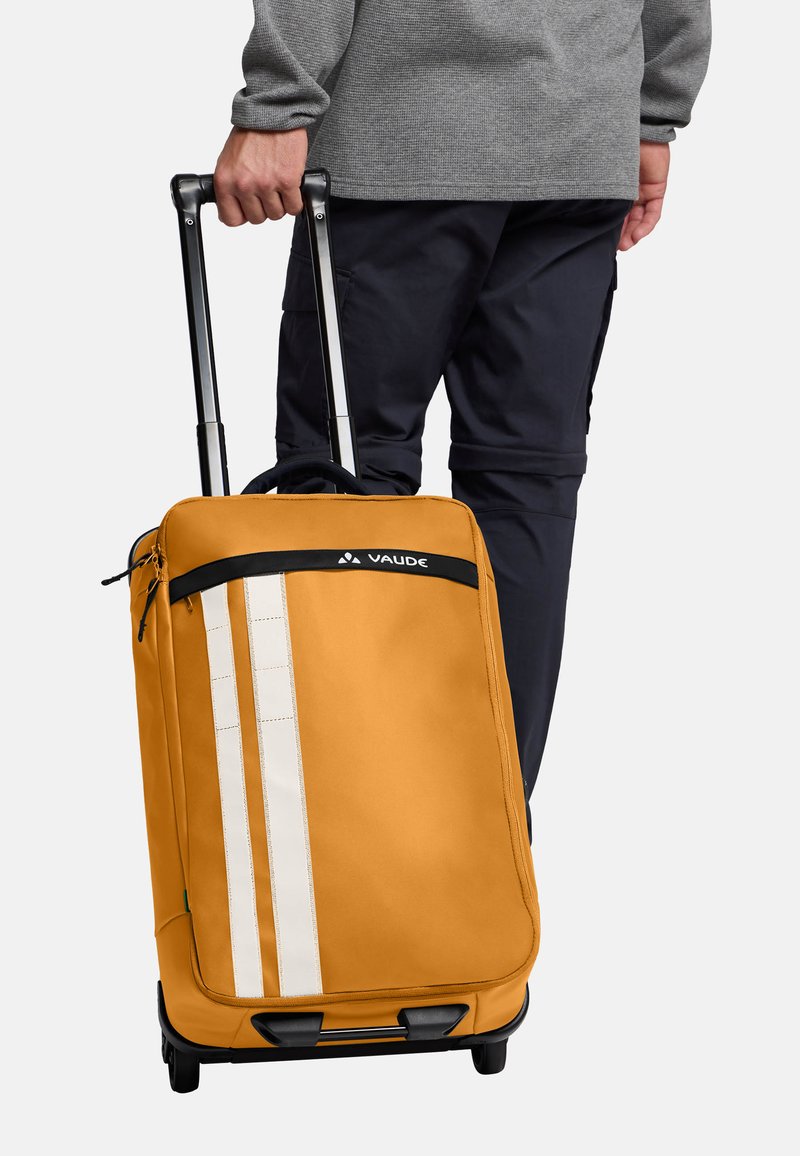 Valigia gialla con superficie liscia, caratterizzata da due strisce verticali bianche e una maniglia superiore. Ha una maniglia trolley nera richiudibile.