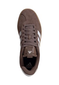 Scarpa sportiva in suede marrone con strisce bianche, chiusura con lacci, suola in gomma e logo sulla linguetta e sul tallone. Texture liscia in tutto il modello.