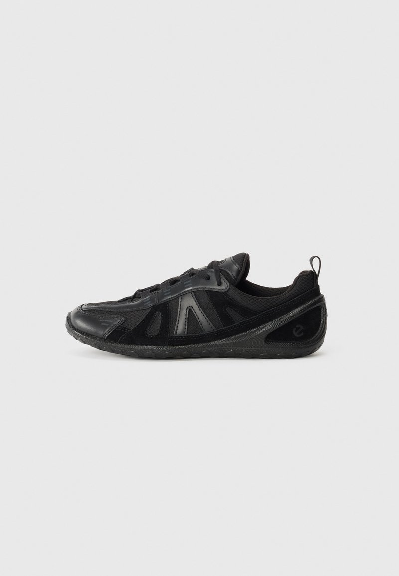 Sneaker nera caratterizzata da una combinazione di pannelli lisci e testurizzati, rete traspirante e suola in gomma flessibile. Il design include dettagli minimi.