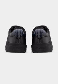 Ζευγάρι μαύρα sneakers Love Moschino, εμφανιζόμενα από πίσω, με γυαλιστερές πίσω επενδύσεις με λογότυπα καρδιάς και χοντρές λαστιχένιες σόλες.