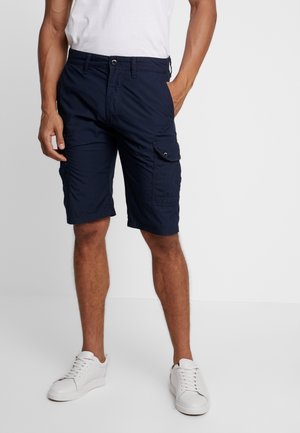 Shorts cargo bleu marine en tissu léger, avec poches latérales, fermeture par bouton et coupe décontractée, assortis à des baskets blanches.