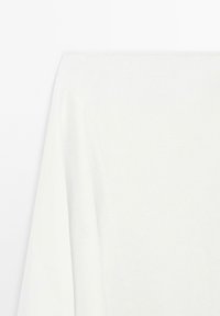 Vit långärmad topp med en mjuk textur, med rund halsringning och avslappnad passform, som framhäver en enkel design och rena linjer.