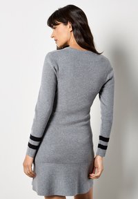 Graues Strickkleid mit tailliertem Oberteil und ausgestellt geschnittenem Saum. Mit schwarzen gestreiften Akzenten an den Ärmeln und klassischem Rundhalsausschnitt.
