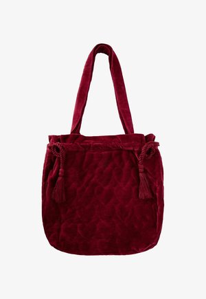 Tiefrote Velours-Tote-Tasche mit langen Tragegriffen, gestepptem Textil und dekorativen geflochtenen Quasten auf jeder Seite.