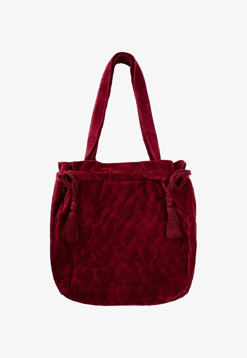 Diep rode fluwelen tote bag met lange handvatten, gequiltde textuur en decoratieve gevlochten kwastjes aan elke zijde.