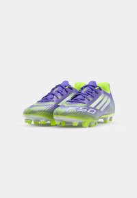 Bottines de football violet et néon vert avec une tige texturée, des accents blancs audacieux et une forme aérodynamique dotée de crampons pour une traction optimale.