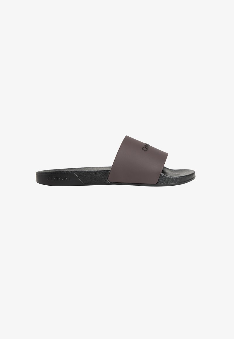 Sandale à glissière Calvin Klein noire et marron foncé avec une large bride et une semelle plate texturée, vue de côté sur fond blanc.