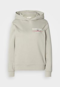 Sweat à capuche beige clair avec impression avant indiquant "GANT 1949" et un petit logo bouclier au-dessus des bord-côtes aux poignets et à l'ourlet.