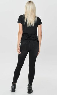 Schwarze enganliegende Leggings aus glattem Stoff mit ausgefranstem Saum, kombiniert mit schwarzen Knöchel-Stiefeln mit dekorativer Hardware.