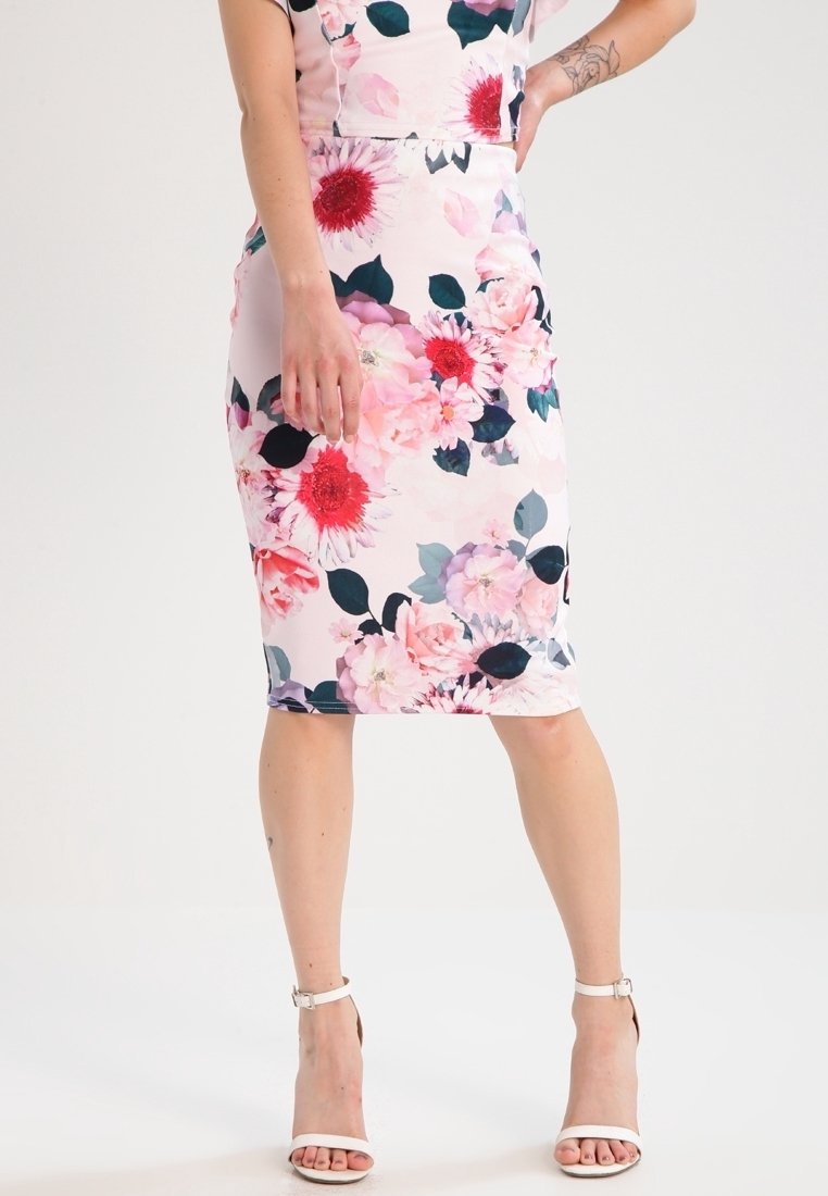 Vestido de lápiz floral con fondo rosa, que presenta grandes flores rojas y rosas y hojas verde oscuro. Tejido suave y diseño hasta la rodilla.