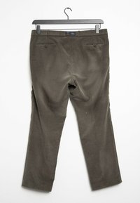 Brown corduroy pants hanging on a black hanger, showing back pockets with buttons, against a plain white background.