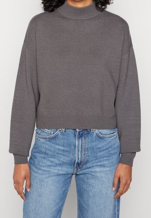 Pull gris court avec un col haut, des poignets et un ourlet côtelés. Associé à un jean en denim bleu clair avec un design classique à cinq poches.