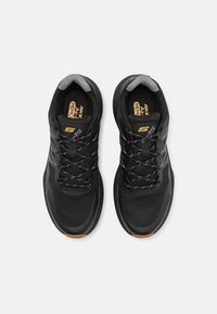 Chaussures de sport noires avec tige en maille, semelles rembourrées et accents gris. Dotées d'un design à lacets et d'une semelle extérieure en caoutchouc texturé.