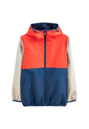 Veste à blocs de couleurs avec le haut rouge, le corps bleu marine et les manches beiges. Confectionnée en tissu léger avec une capuche et une fermeture éclair à l'avant.