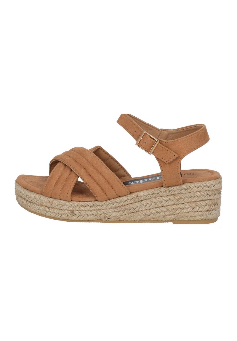 Tan suede wedge sandal with crisscross straps, adjustable ankle buckle, and woven jute sole. Smooth texture and round toe design.