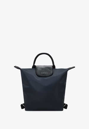 Bolsa tote impermeable de nylon negro con solapa de cuero negro texturizado y asa superior, que cuenta con correas ajustables y detalle del logo en la solapa.