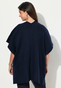 Marinblå stickad poncho med avslappnad passform, korta ärmar, ribbad textur och rundad halsringning, med vertikala sömdetaljer.