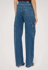 Džínové kalhoty s širokými nohavicemi v středně modré barvě. Obsahují dvě boční kapsy na cargo a klasické zadní nášivné kapsy. Vyrobeno z pevné džínoviny.