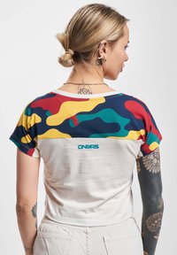 Majica s kratkimi rokavi z barvnim kamuflažnim vzorcem na ramenskih delih, kremasta telesa in modrim logotipom na sredi hrbta. Bombažna tkanina.