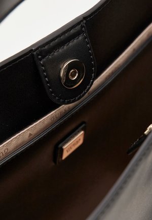 Wnętrze czarnej skórzanej torebki ze złotymi elementami, zapięcie na guzik oraz beżowa podszewka z powtarzającym się wzorem logo.