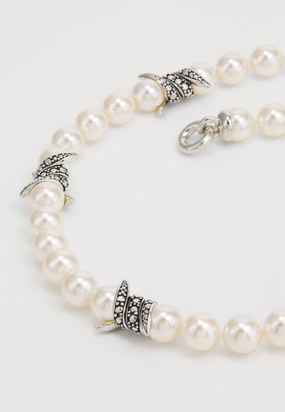 Collier en perles comprenant des perles blanches lisses et rondes, avec des éléments en métal argenté détaillés et des accents décoratifs. Fermoir sécurisé.