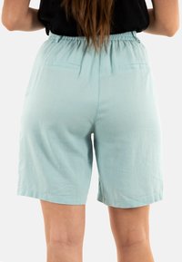 Pantaloni corti azzurri chiari, alla lunghezza del ginocchio, con vita elasticizzata e due tasche posteriori. Il materiale appare morbido e liscio senza motivi visibili.