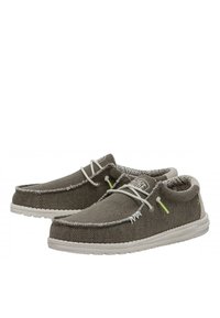 Zapatos de textil grises con costuras blancas, punta redonda, suela blanca y detalles decorativos de cordones. Tela texturizada con forro interior estampado.