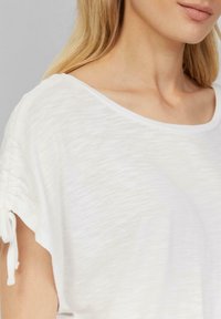 Witte, lichtgewicht top met een textuurafwerking, brede halslijn en gathered mouwen met trekkoordsluitingen. Eenvoudig, casual ontwerp.