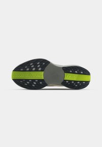 Semelle d’une chaussure de course Nike avec une bande de roulement noire, une semelle intermédiaire grise et une bande vert néon portant les inscriptions « NIKE » et « PEGASUS TURBO 2.0 ».