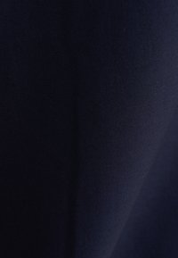 Nahaufnahme von glattem, dunkel marineblauem Stoff mit dezentem diagonalen Schatten und sichtbaren feinen Texturdetails.