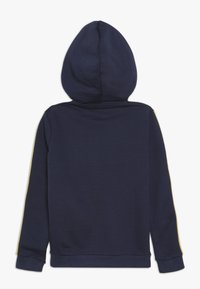 Navyblauwe hoodie met een zachte textuur, voorzien van een centrale naad, lange mouwen en een capuchon. Gele accenten lopen langs elke mouw.