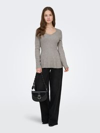 Haut gris à manches longues côtelées avec un col en V, assorti à un pantalon noir à jambes larges et un sac bandoulière noir avec un rabat texturé et une boucle métallique.