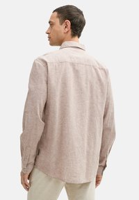 Helles pinkes Leinenhemd mit langen Ärmeln, Knopfmanschetten und einem klassischen Kragen, das über ein strukturiertes Gewebe und einen leicht abgerundeten Saum verfügt.