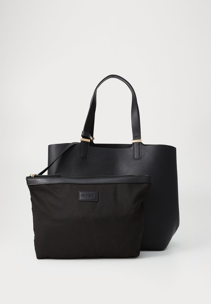 Grand sac cabas noir avec deux poignées derrière une petite pochette noire zippée avec une bordure en cuir et une étiquette indiquant "Pieces."