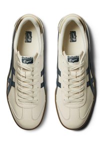 Béžové kožené tenisky s tmavě modrými akcenty, kulatou špičkou, klasickým šněrováním, texturovanou gumovou podrážkou a tkaným logem na jazyku.