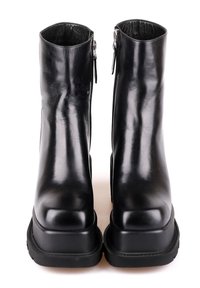 Bottes en cuir noir mi-mollet avec fermetures éclair latérales, bouts carrés et semelles épaisses en caoutchouc, présentées droites de face sur un fond blanc.