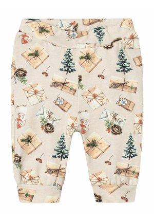 Pantalon bébé beige avec imprimé sur le thème de Noël comprenant des cadeaux emballés, des sapins, des pommes de pin et de petites baies rouges.