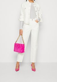 Vit denimjacka, åtsittande grå topp, vita byxor, livfullt rosa fuskpälshandväska med guldchain, och rosa klackar med hjärtprydnader.