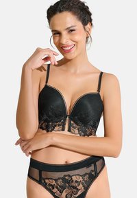 Ensemble de lingerie noir comprenant un soutien-gorge avec des bonnets rembourrés, un overlay en dentelle, des motifs floraux et des accents en maille transparente. Le slip assorti présente un design floral.