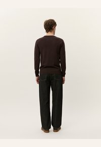 Barna, hosszú ujjú pulóver, illeszkedő aljjal és mandzsettával, laza, sötét farmerekkel párosítva. Simaság, minimalista dizájn.