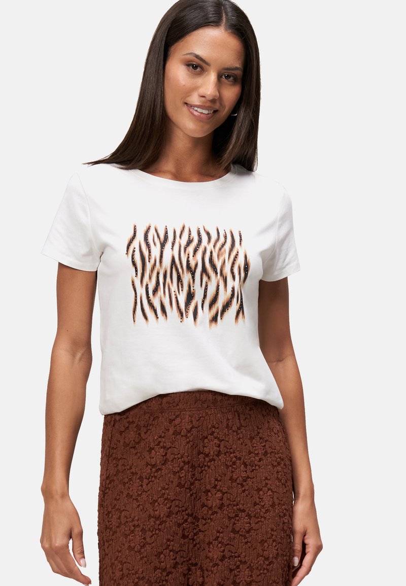 T-shirt en coton blanc présentant un motif abstrait ondulé marron et noir sur le devant. Manches courtes et col rond.