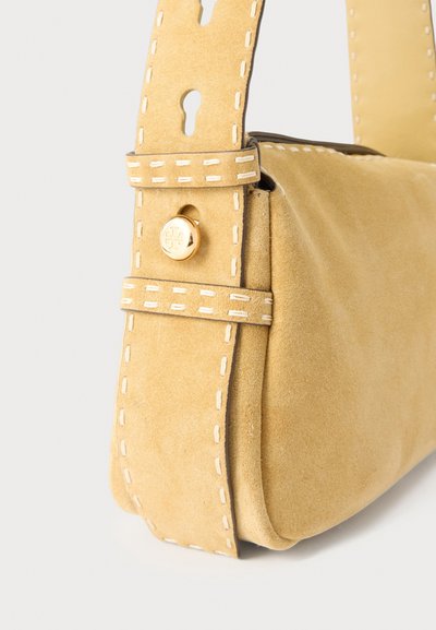 Τσάντα χειρός από μπεζ σουέντ με χοντρό λουρί, λευκές ραφές, χρυσό κουμπί με χαραγμένο λογότυπο και άνοιγμα σε σχήμα κλειδαρότρυπας στο λουρί.