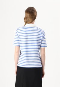 Kortermet polo skjorte i hvit med blå og lyseblå horisontale striper. Har klassisk krage og lett buet nederkant.