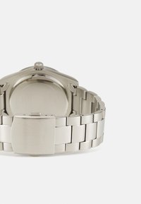 Silberner Edelstahluhren mit polierter Oberfläche, ausgestattet mit einem schlanken Armband und einem sicheren Verschluss. Das Design umfasst ein minimalistisches rundes Gehäuse.